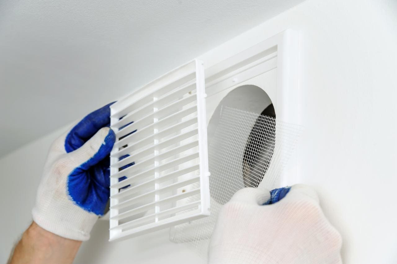 Ventilation dans le nouveau bâtiment Une main installe une partie de la ventilation dans le nouveau bâtiment
