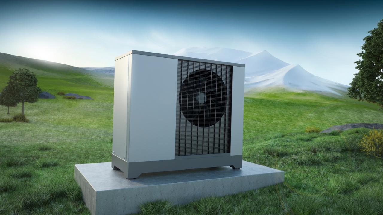 La photo montre une pompe à chaleur à air sur un pré devant un panorama de montagnes